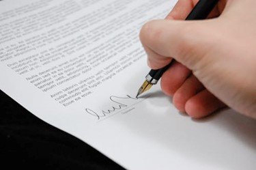 Person signing a timeshare contract with caution